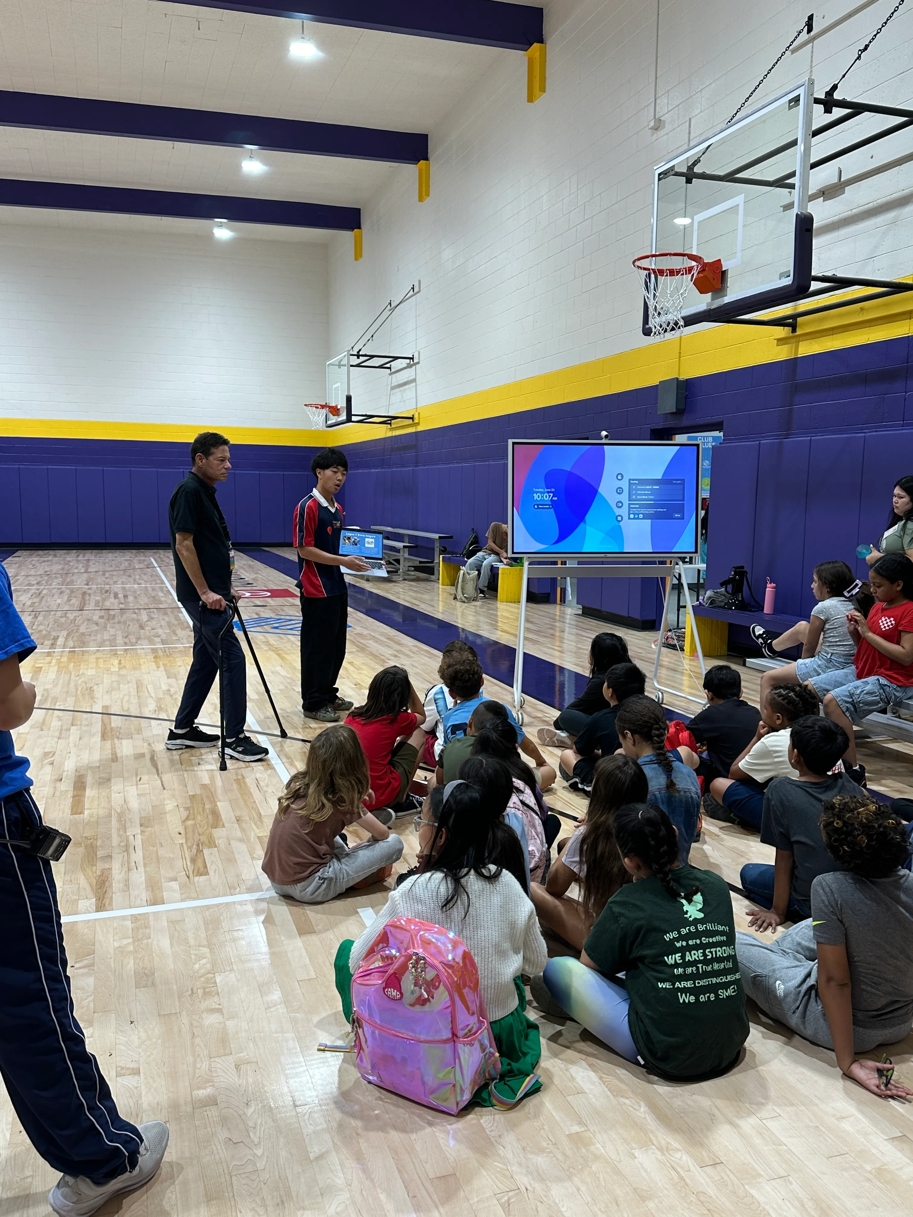 Students listening to a STEM Inspire presentation in a community gym.